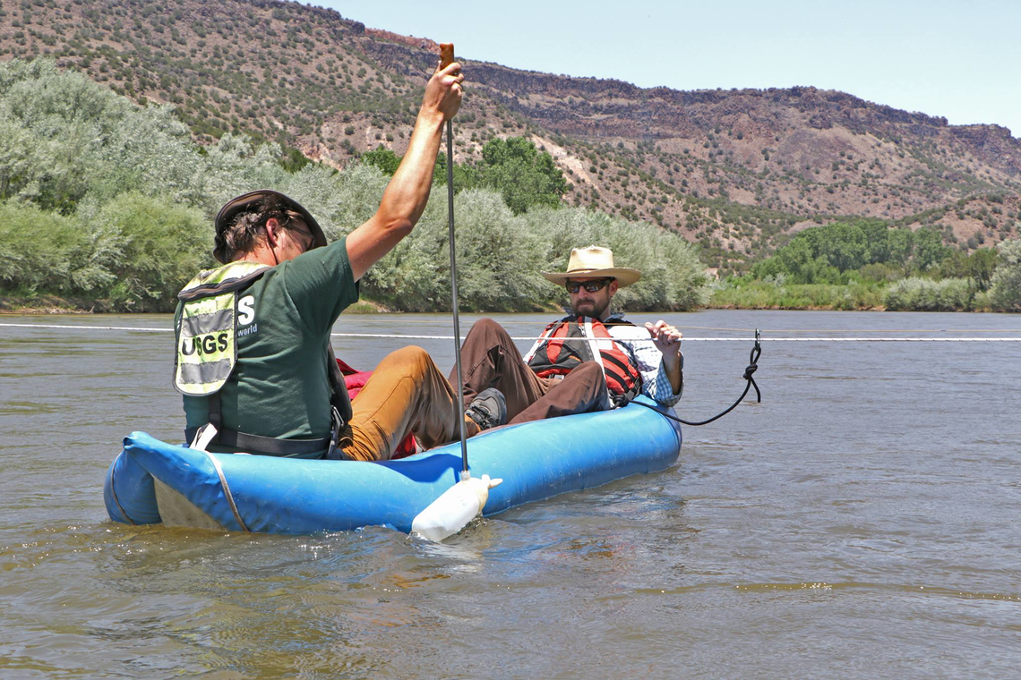 Two USGS employees, in a boat, sampling suspended sediment concentration in the Rio Grande River