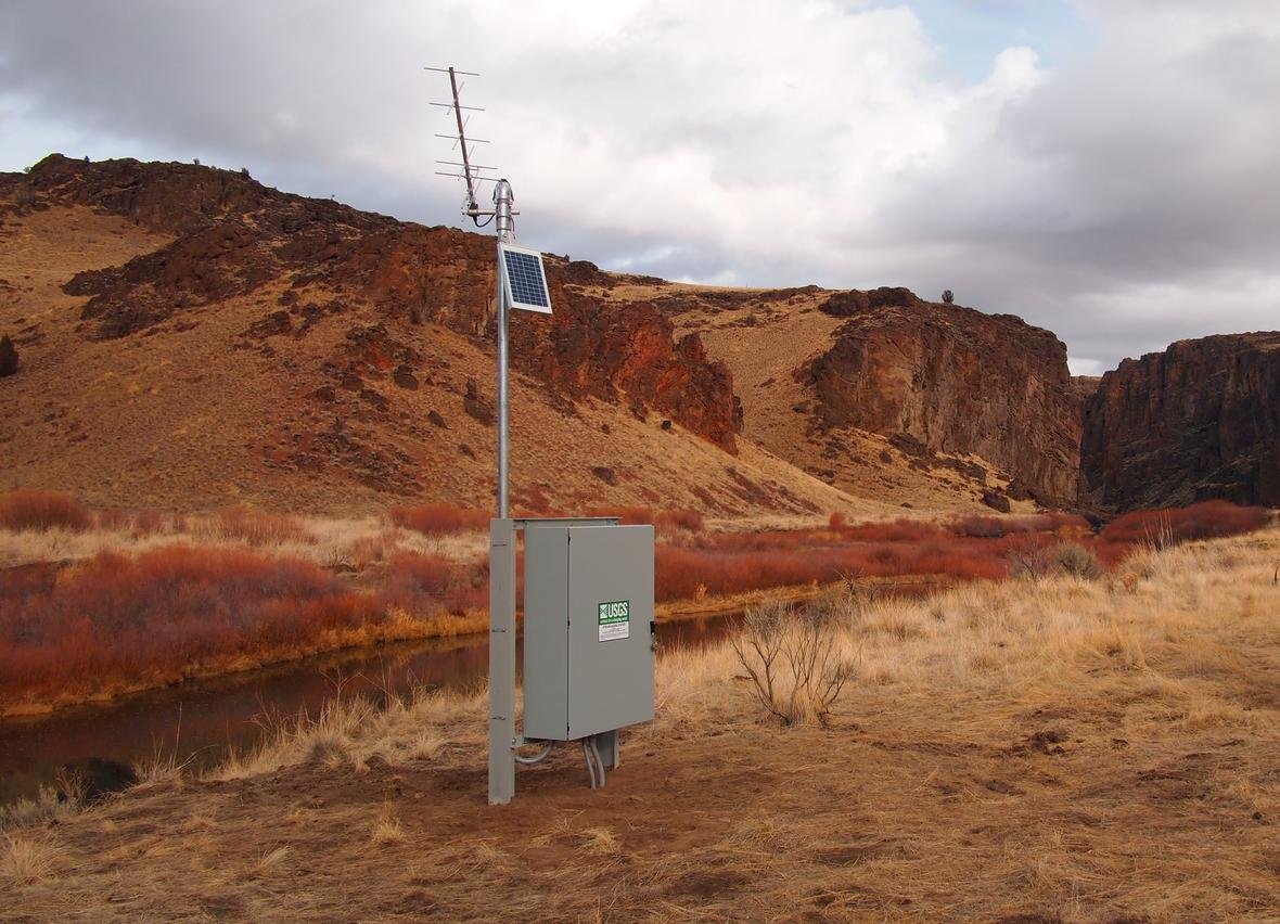 A photo of a streamgage on a riverbank in a canyon.